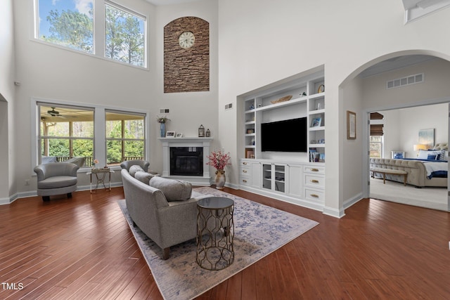 5928 Terrington Ln, Raleigh, NC 27606 - living area featuring visible vents, built in shelves, baseboards, arched walkways, and dark wood finished floors