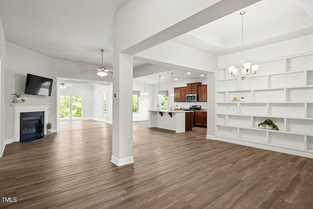 unfurnished living room with a chandelier, dark wood-style floors, a glass covered fireplace, ceiling fan, and baseboards