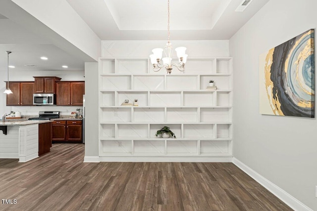 unfurnished dining area featuring dark wood-style floors, a chandelier, baseboards, recessed lighting, and a tray ceiling