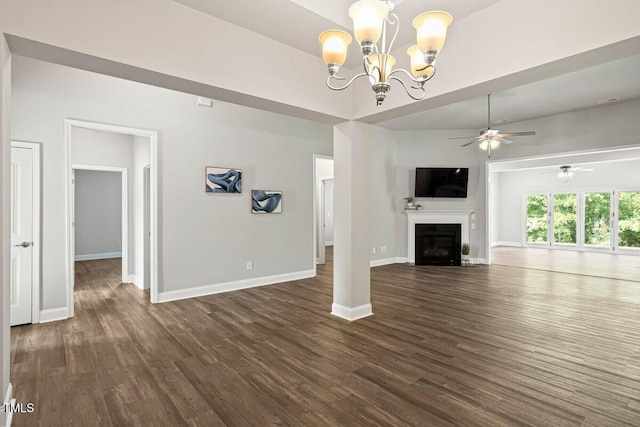 unfurnished living room with dark wood-type flooring, a ceiling fan, baseboards, and a chandelier