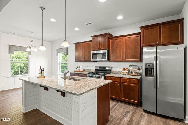 kitchen with appliances with stainless steel finishes, a sink, dark wood-style floors, light stone counters, and recessed lighting