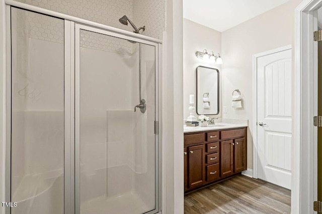 bathroom with a shower stall, wood finished floors, and double vanity