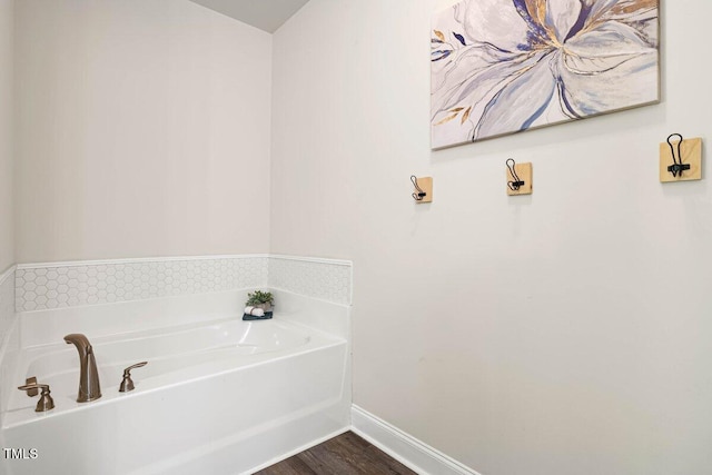 full bathroom featuring baseboards, a garden tub, and wood finished floors
