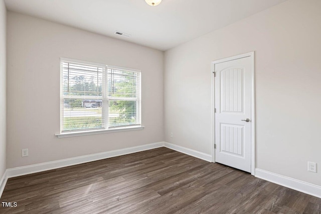 spare room with dark wood-style flooring and baseboards