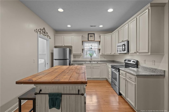 887 Thrush Dr, Vass, NC 28394 - kitchen featuring a breakfast bar, a sink, light wood finished floors, stainless steel appliances, and visible vents