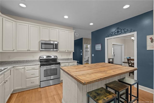 887 Thrush Dr, Vass, NC 28394 - kitchen with wooden counters, appliances with stainless steel finishes, a center island, light wood-type flooring, and white cabinets