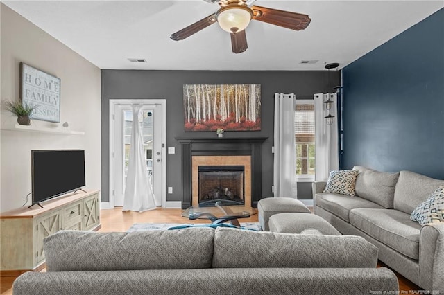 887 Thrush Dr, Vass, NC 28394 - living room with light wood-style flooring, a ceiling fan, a tile fireplace, and visible vents