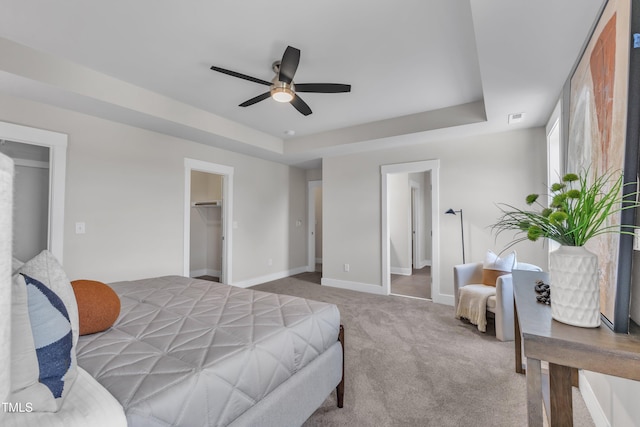 706 Fireball Ct, Knightdale, NC 27545 - carpeted bedroom featuring a tray ceiling, baseboards, a spacious closet, and a ceiling fan