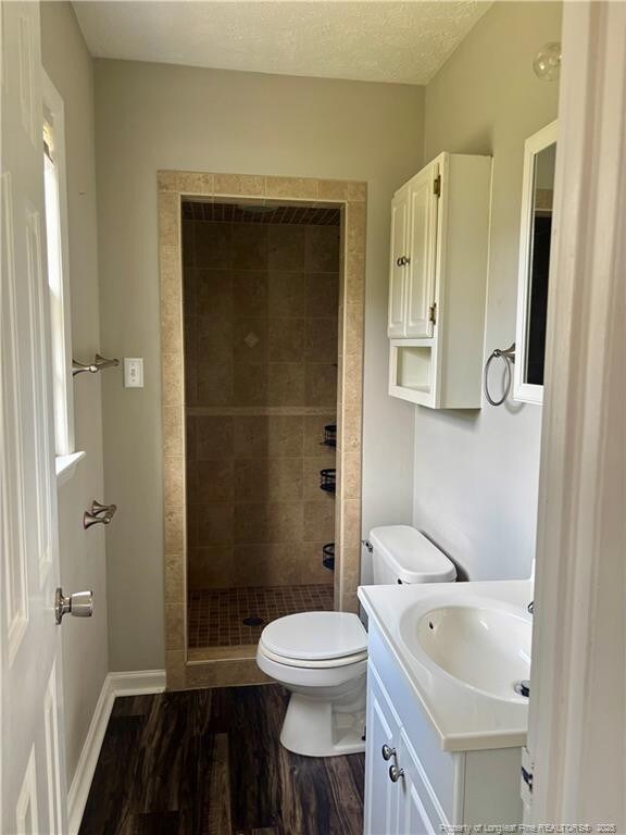 5704 Selkirk Pl, Fayetteville, NC 28304 - full bathroom with vanity, a stall shower, a textured ceiling, toilet, and wood finished floors