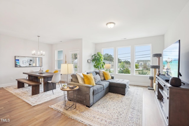 living area featuring light wood finished floors, baseboards, and an inviting chandelier