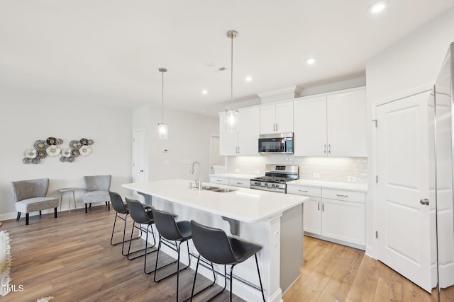 kitchen with tasteful backsplash, a kitchen island with sink, a sink, stainless steel appliances, and a breakfast bar area