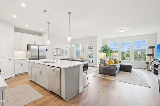 kitchen featuring a sink, open floor plan, light wood-style floors, and stainless steel appliances