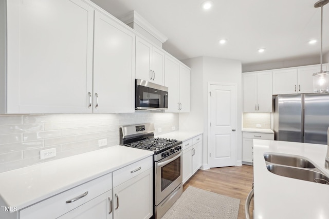 kitchen featuring white cabinets, light countertops, appliances with stainless steel finishes, recessed lighting, and light wood finished floors