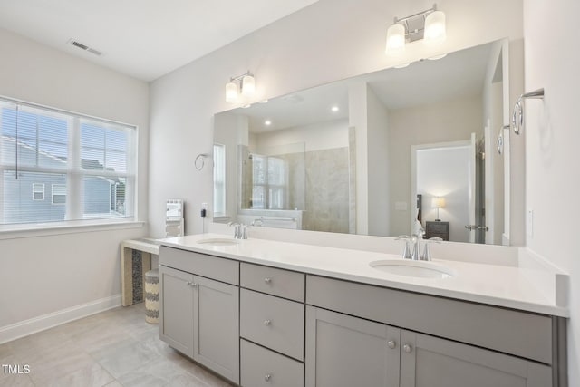 bathroom with a tile shower, double vanity, a sink, and visible vents