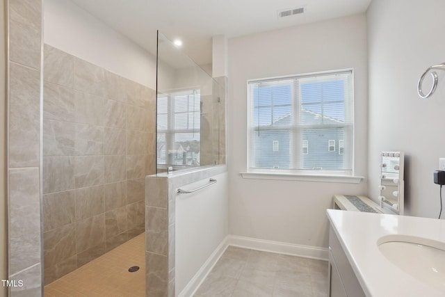 bathroom with a walk in shower, vanity, baseboards, and visible vents
