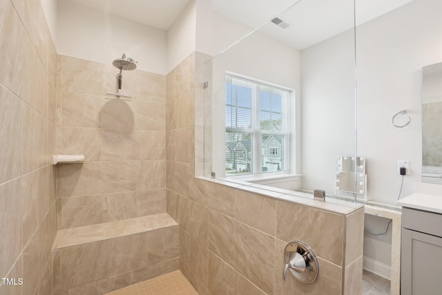 full bath with a tile shower, vanity, and visible vents