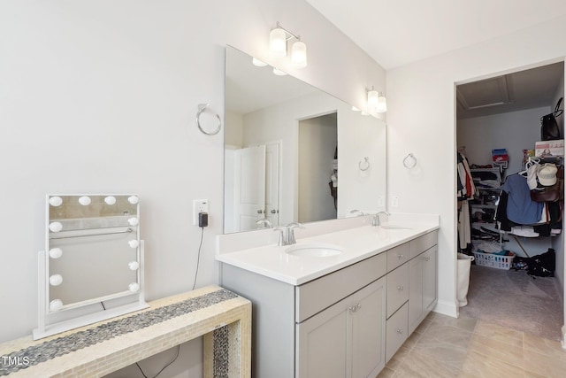 full bath with a walk in closet, double vanity, and a sink