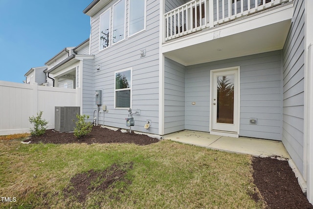 property entrance with central air condition unit, a lawn, a patio, fence, and a balcony