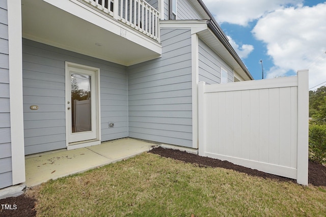 view of exterior entry featuring a patio and a balcony