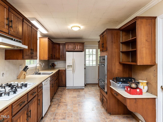 kitchen featuring under cabinet range hood, a sink, white appliances, and a wealth of natural light