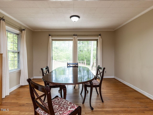 dining space featuring crown molding, baseboards, and light wood finished floors