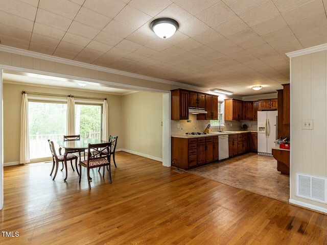 dining room featuring wood finished floors, baseboards, ornamental molding, and visible vents
