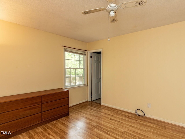 unfurnished room with light wood-type flooring, ceiling fan, baseboards, and a textured ceiling