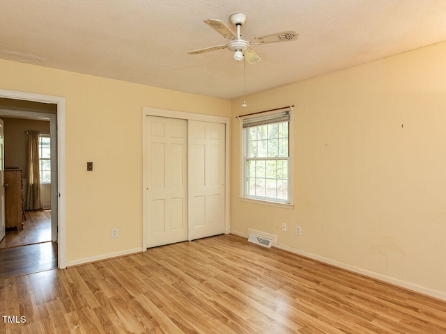 unfurnished bedroom with visible vents, baseboards, light wood finished floors, and a closet