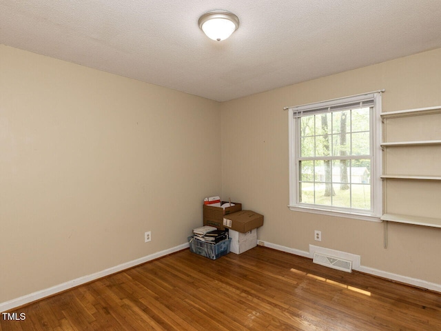spare room with visible vents, baseboards, and wood finished floors