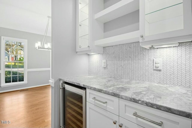 102 Cockleshell Ct, Cary, NC 27513 - bar with light wood-style floors, an inviting chandelier, a dry bar, wine cooler, and backsplash
