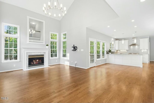 102 Cockleshell Ct, Cary, NC 27513 - unfurnished living room with a notable chandelier, baseboards, recessed lighting, light wood-style flooring, and a premium fireplace