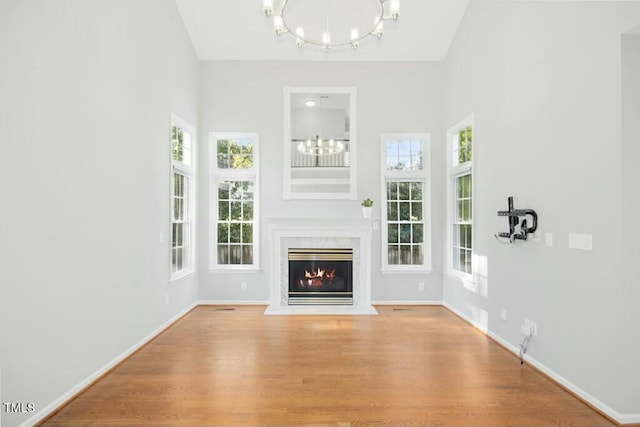 102 Cockleshell Ct, Cary, NC 27513 - unfurnished living room featuring a towering ceiling, an inviting chandelier, wood finished floors, and a healthy amount of sunlight