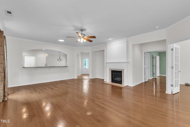 113 Dowington Ln, Cary, NC 27519 - unfurnished living room featuring ceiling fan, a glass covered fireplace, wood finished floors, crown molding, and baseboards