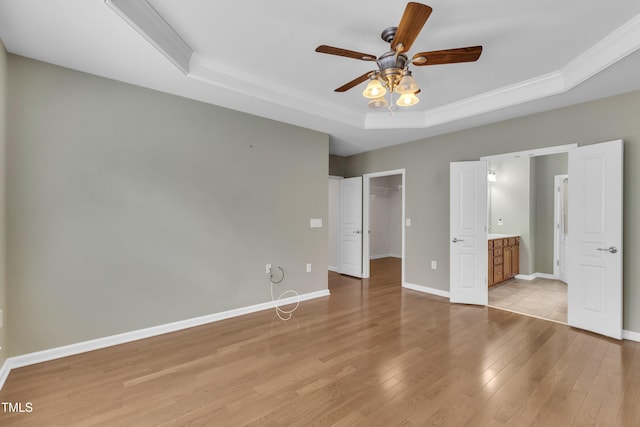 113 Dowington Ln, Cary, NC 27519 - unfurnished bedroom with a tray ceiling, crown molding, light wood-type flooring, baseboards, and a spacious closet