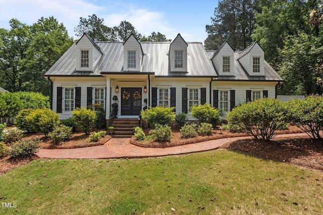 cape cod home with a front yard and metal roof