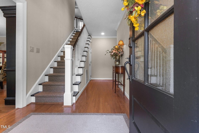 entrance foyer with wood finished floors, ornamental molding, stairs, baseboards, and recessed lighting