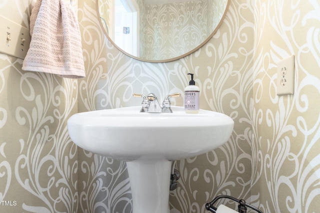 half bath with wallpapered walls and a sink