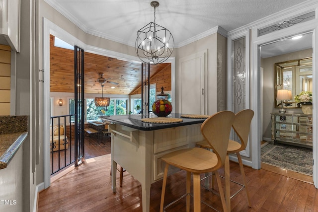 dining space with wood finished floors, a chandelier, crown molding, and baseboards