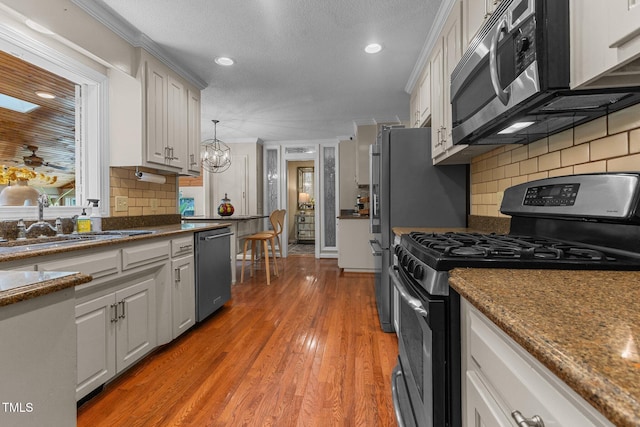 kitchen with stainless steel appliances, a sink, recessed lighting, backsplash, and white cabinets