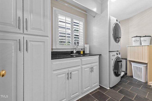 clothes washing area with estacked washer and dryer and cabinet space