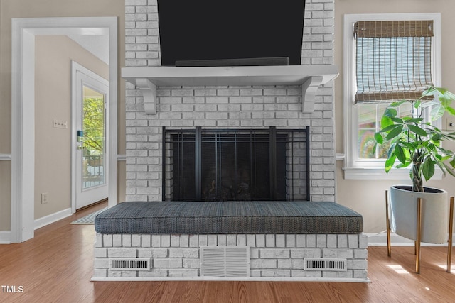 detailed view of a brick fireplace, wood finished floors, and baseboards