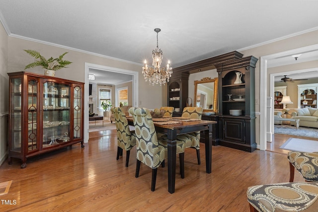 dining area with a chandelier, light wood finished floors, ornamental molding, and a ceiling fan