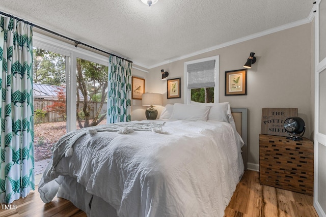 bedroom with a textured ceiling, wood finished floors, crown molding, baseboards, and access to exterior