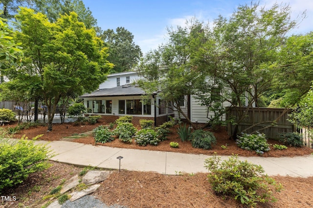 view of front of home with fence, brick siding, and metal roof