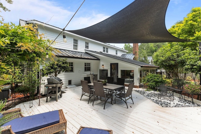 wooden terrace featuring outdoor dining area and a grill