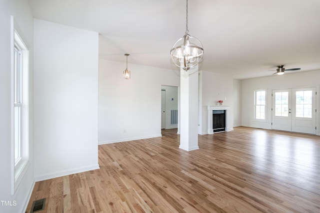 unfurnished living room featuring light wood finished floors, a chandelier, ceiling fan, and baseboards