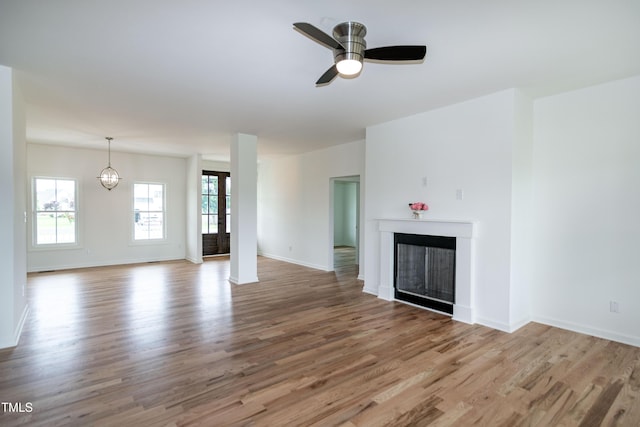 unfurnished living room with wood finished floors, a fireplace, ceiling fan, and baseboards