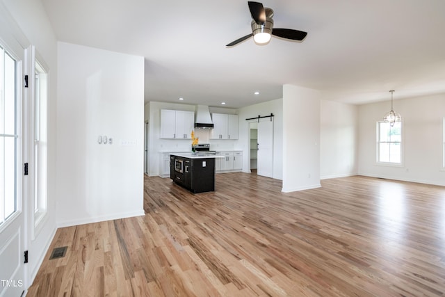 unfurnished living room with a barn door, a ceiling fan, light wood-style flooring, baseboards, and recessed lighting