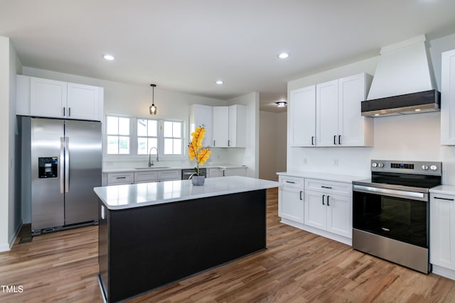 kitchen featuring stainless steel appliances, custom range hood, a sink, light countertops, and light wood finished floors