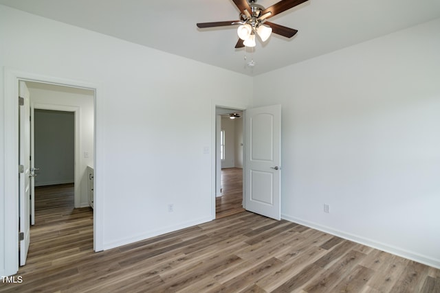 unfurnished bedroom with wood finished floors, baseboards, and a ceiling fan